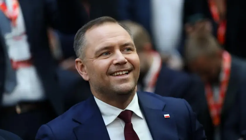 Uśmiechnięty mężczyzna w garniturze z polską flagą na klapie. Czy to jego styl życia wyjaśnia, dlaczego urząd prezydenta jest uznawany za najdroższy w utrzymaniu w całej Europie Środkowej?
