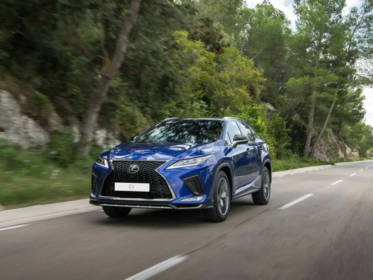 Niebieski Lexus RX 450h jedzie po krętej drodze wśród zieleni.