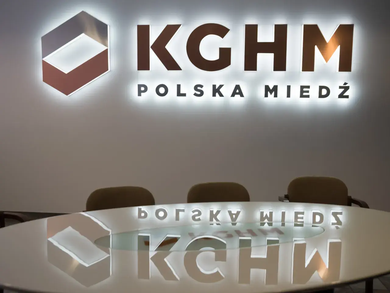 Logo KGHM Polska Miedź i odbicie na stole. Czy Konfederacja poprze ustawę o obniżeniu podatku miedziowego w zamian za ustępstwa?