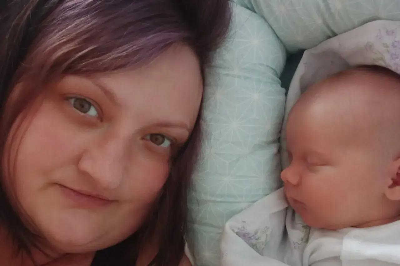 Anna Lew-Tusk, neonatolog, odpoczywa obok śpiącego noworodka.