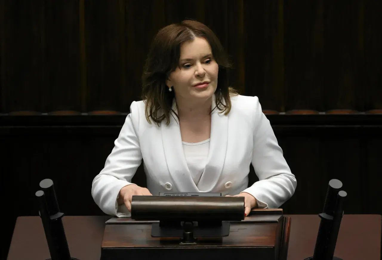Anna Krupka w białej marynarce przy mównicy. Czy wiceprezes PiS nie dostaje pieniędzy za funkcję?
