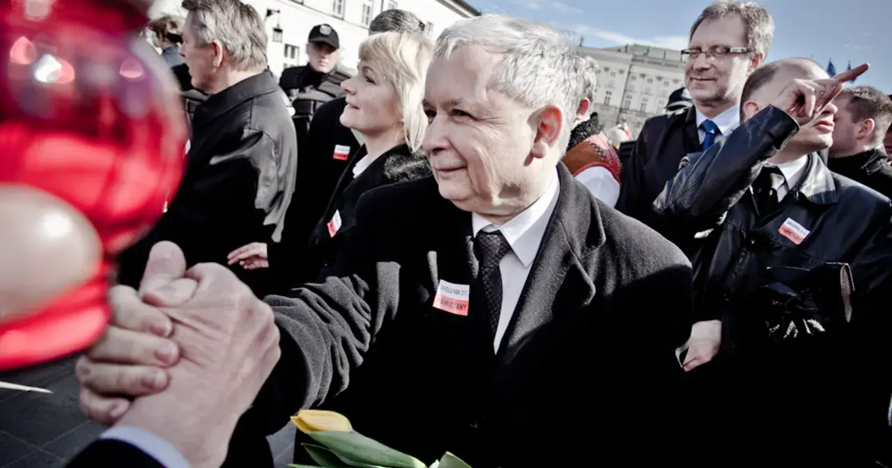 Jarosław Kaczyński ściska dłoń, w tle ludzie i czerwone balony.