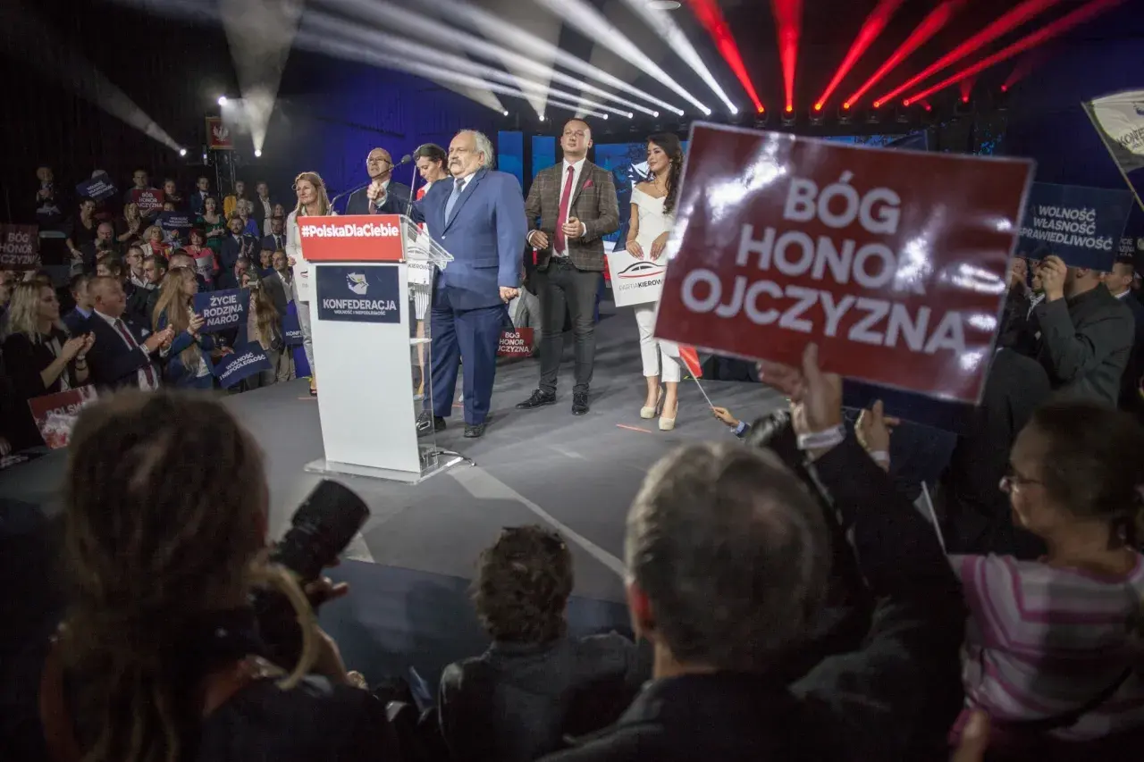 Kto z polityków Konfederacji stoi za nowym projektem ustawy o dobrowolnym ZUS? Na scenie przemawia Krzysztof Bosak, a obok niego stoją inni politycy partii.
