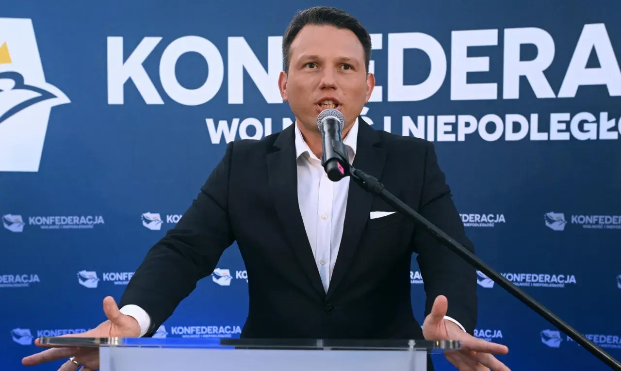 Mężczyzna w garniturze przemawia do mikrofonu na tle baneru Konfederacji. Dyskutuje, dlaczego KO chce odebrać dotacje partii opozycyjnej poprzez nowelizację kodeksu wyborczego.