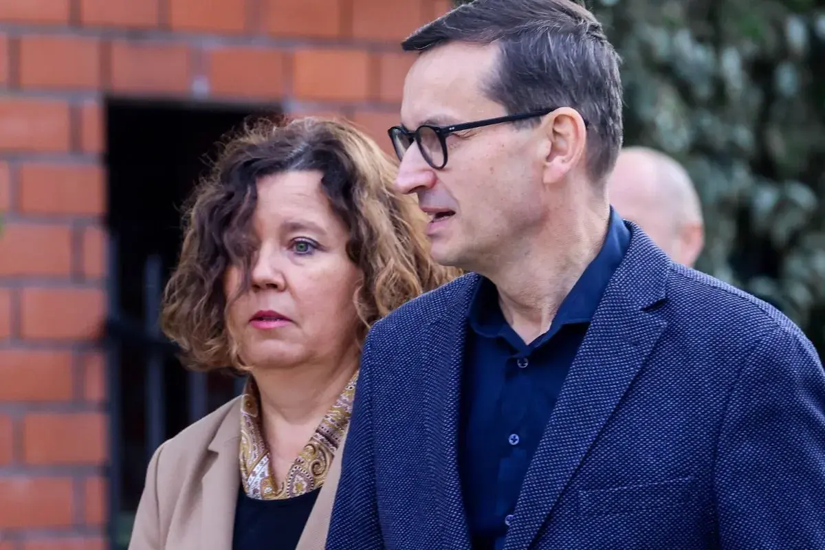 Iwona i Mateusz Morawieccy w zbliżeniu, na tle ceglanego muru.
