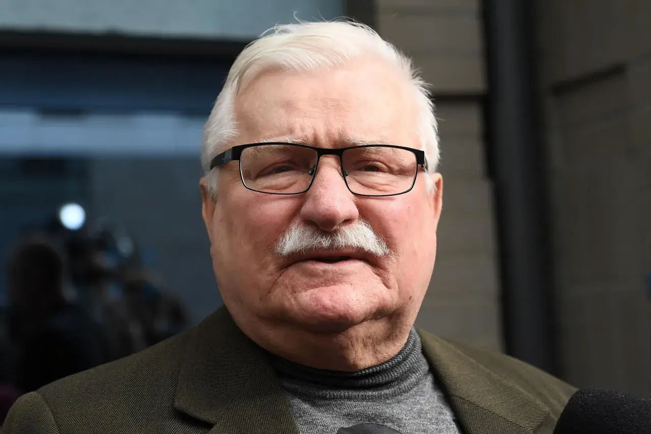 Lech Wałęsa w okularach i z wąsami, w swetrze i marynarce. W tle niewyraźne postacie.