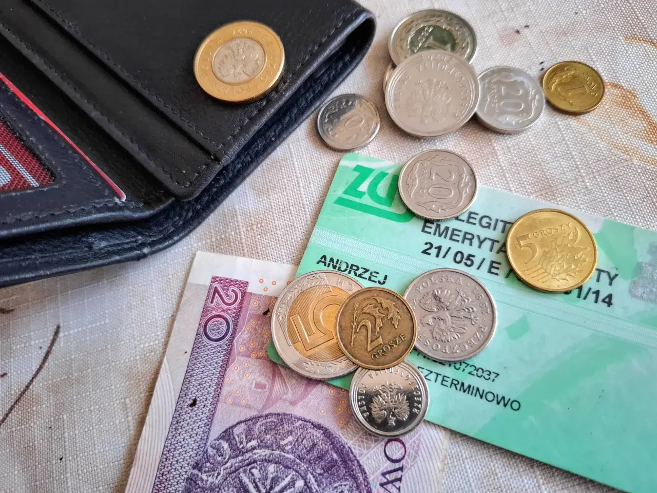 Portfel, polskie monety i banknot 20 zł na zielonej legitymacji emerytalnej. Dlaczego KO poparła reformę renty wdowiej mimo obaw o budżet?