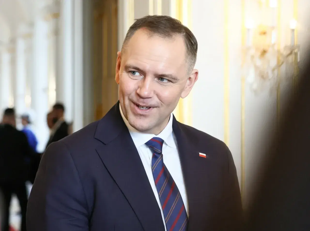 Prezydent Andrzej Duda w garniturze, z flagą Polski na klapie. Zastanawiasz się, ile zarabia prezydent Duda?