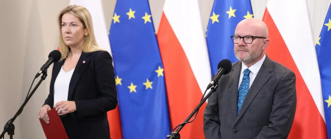 Kobieta i mężczyzna przed mikrofonami na tle flag Polski i UE. Czy ustawa o "teście na polaka" ma szansę przejść przez sejm w marcu?