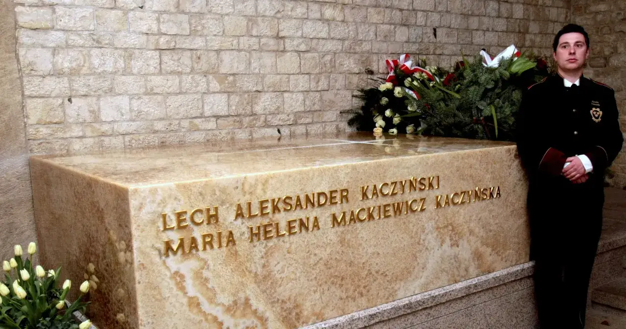 Grób Kaczyńskich na Wawelu. Uroczysty pomnik z imionami i nazwiskami, obok warty żołnierz i wieniec.