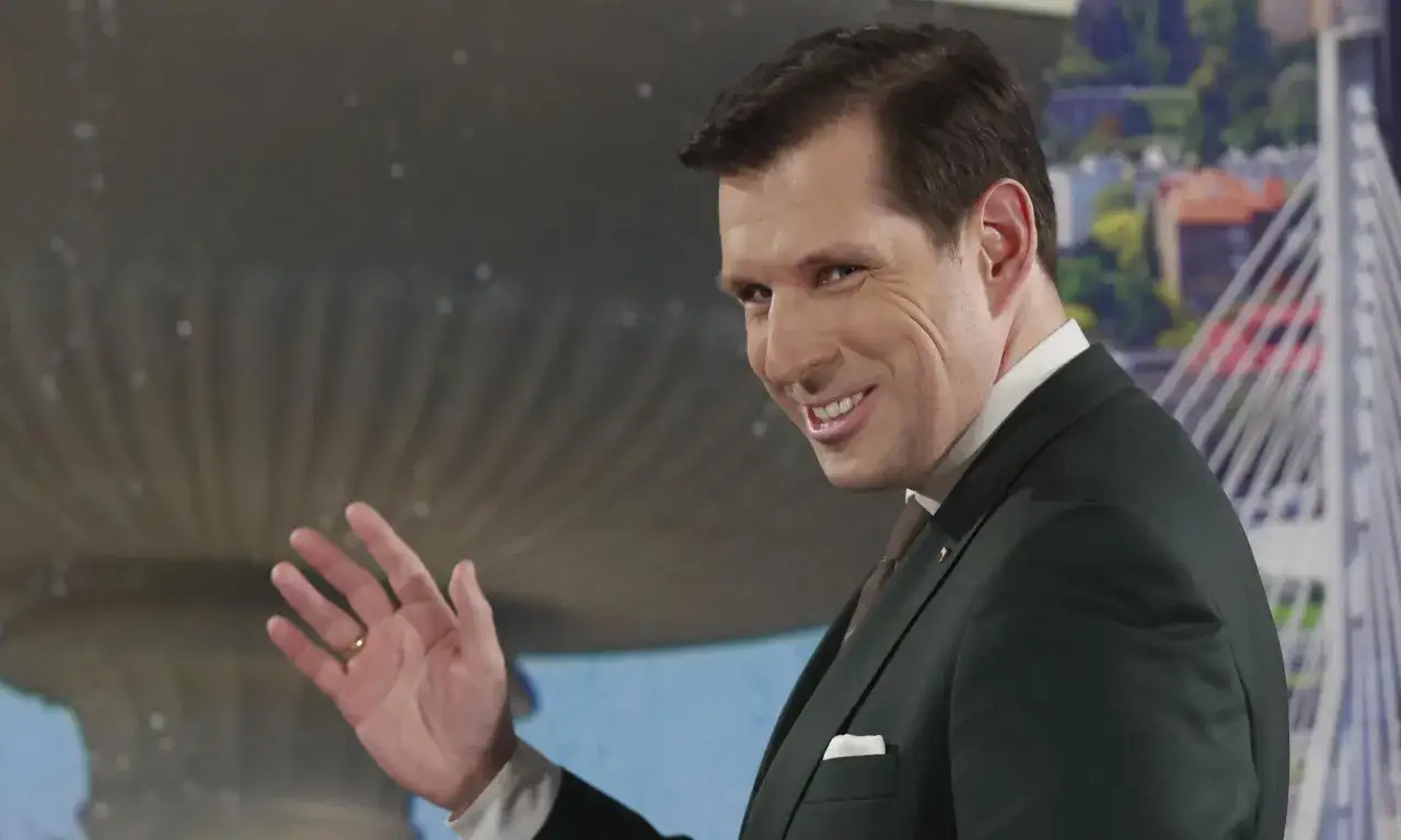 Tobiasz Bocheński, uśmiechnięty i machający, w garniturze. Dlaczego jest 