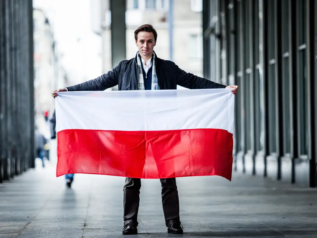 Młody mężczyzna trzyma polską flagę. Czy to symbol tego, dlaczego Krzysztof Bosak domaga się debaty o Chinach i Indiach zamiast o UE?