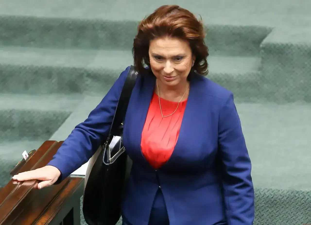 Kobieta w granatowej marynarce i czerwonej bluzce, z torbą na ramieniu, schodzi po zielonych schodach. Ile lat ma Kidawa-Błońska?