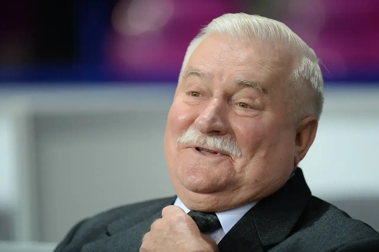 Lech Wałęsa, z charakterystycznym wąsem, poprawia krawat. Jego spojrzenie sugeruje refleksję nad tym, co zrobił dla wolności.