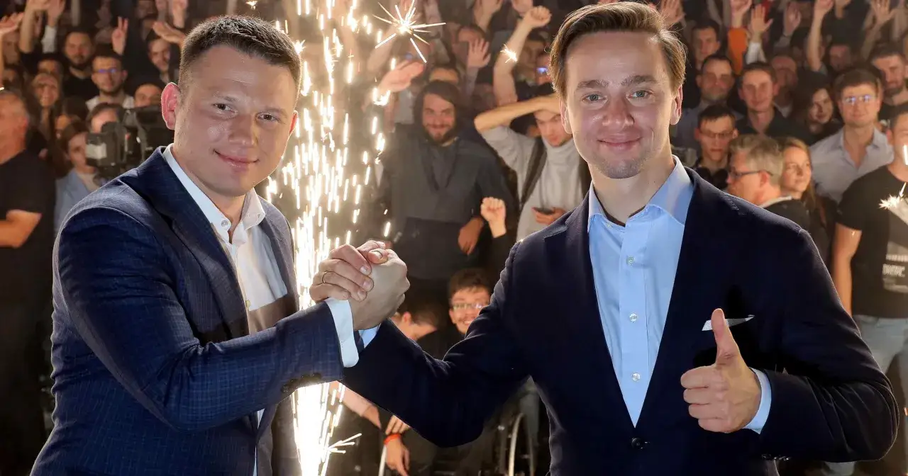 Dwóch polityków Konfederacji ściska sobie dłonie na tle tłumu i fajerwerków. Kto z nich ma największe szanse na wejście do rządu technicznego?