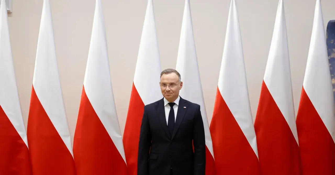 Prezydent Duda stoi przed polskimi flagami. Zastanawiamy się, dlaczego prezydent nie podpisał ustawy o mowie nienawiści przed marcem 2026.