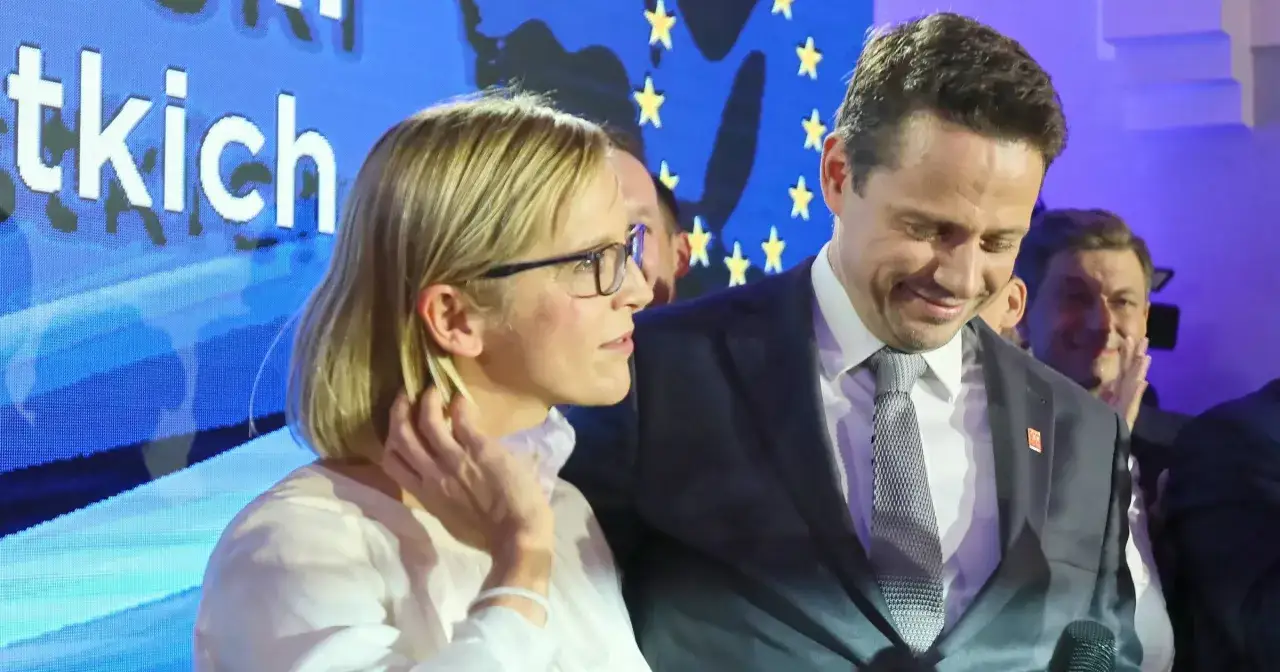 Małgorzata Trzaskowska w okularach i mężczyzna w garniturze na tle niebieskiego ekranu z gwiazdami.