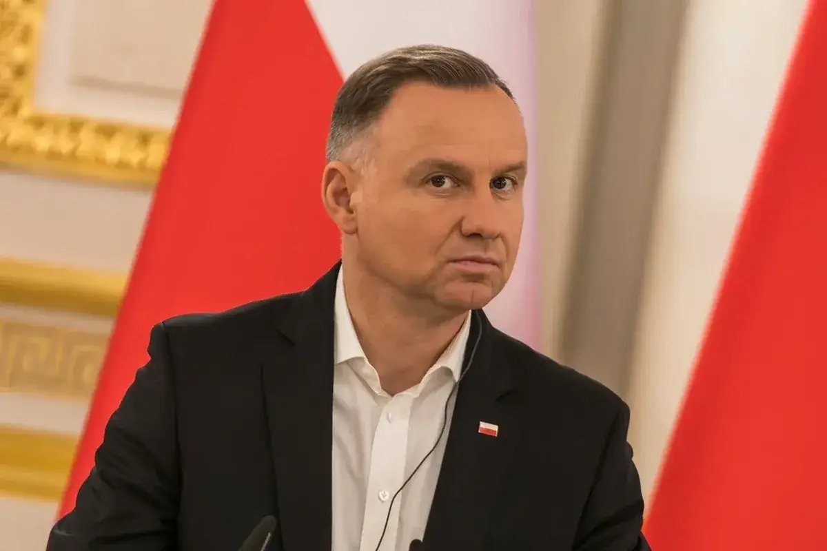 Prezydent Andrzej Duda z zamyśloną miną, na tle flagi Polski. Dyskutuje, dlaczego prezydent zapowiada veto wobec ustawy o wyborze sędziów do KRS.