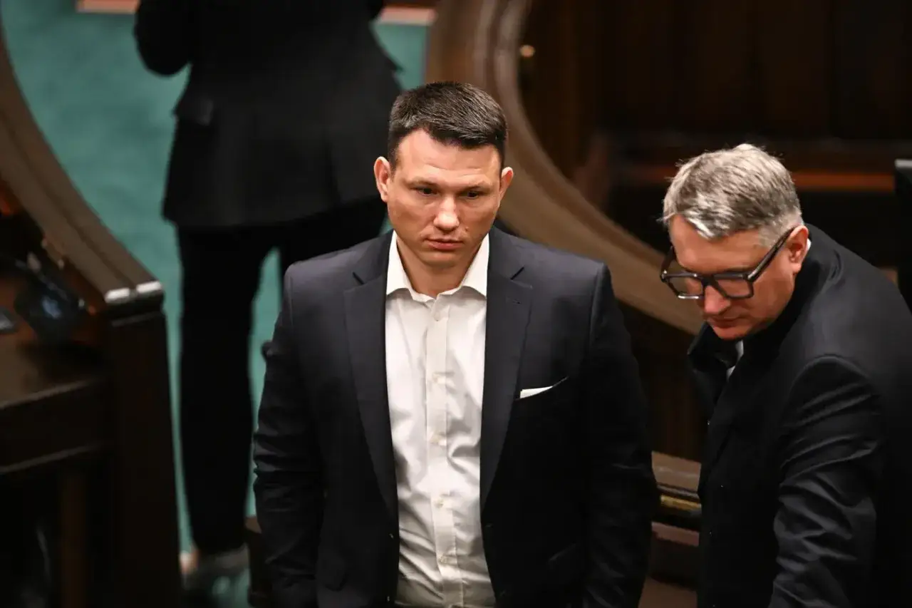 Dwóch mężczyzn w garniturach, jeden z nich to Sławomir Mentzen. Dyskutują, dlaczego partia Mentzena chce podwyższenia limitu kasowego PIT do 2 mln złotych.