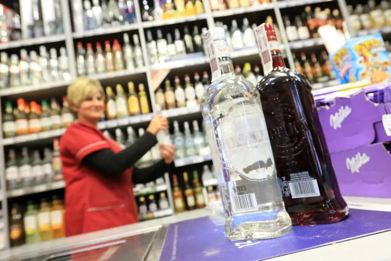 Butelki wódki na pierwszym planie, za nimi ekspedientka w sklepie z alkoholem. Czy ustawa o nocnej prohibicji od godziny 22 obejmie całą Polskę?