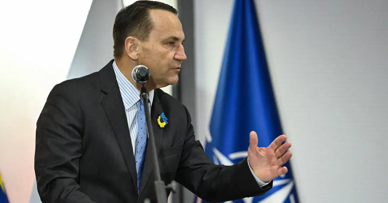 Radosław Sikorski, z ukraińską przypinką, przemawia na tle flagi NATO, pokazując, dlaczego walczy o większe wpływy w polityce zagranicznej koalicji.