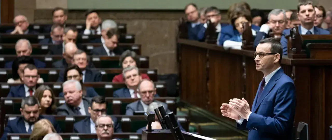 Poseł przemawia na forum, a w tle siedzą inni politycy. Czy Donald Tusk faktycznie zamierza wprowadzić stan wyjątkowy w związku z sytuacją w Izraelu?