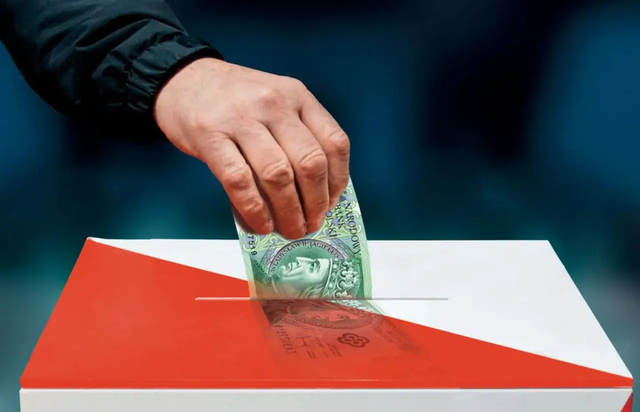 Dłoń wkłada banknot 100 zł do urny wyborczej w barwach narodowych.