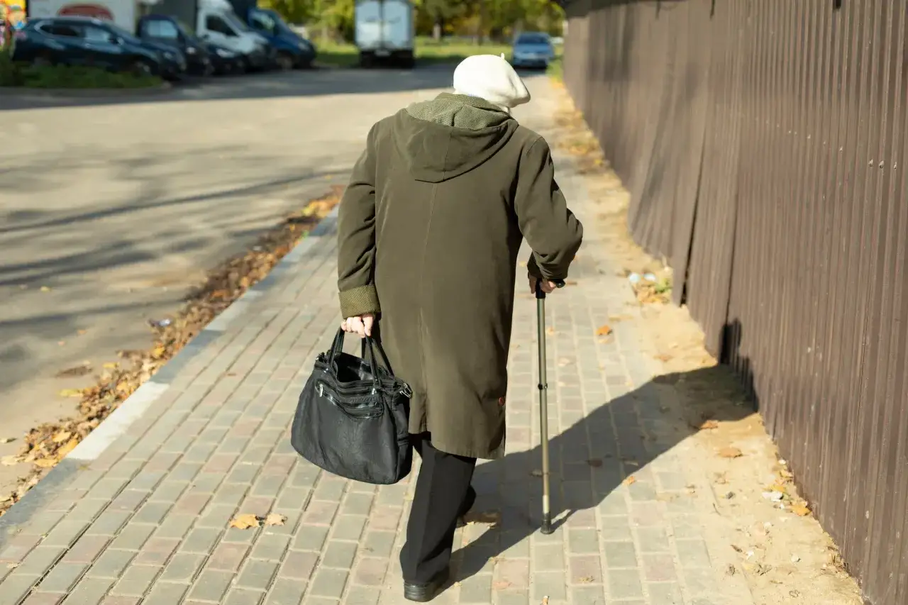Starszy pan z laską i torbą idzie chodnikiem. Dlaczego KO poparła reformę renty wdowiej mimo obaw o budżet?