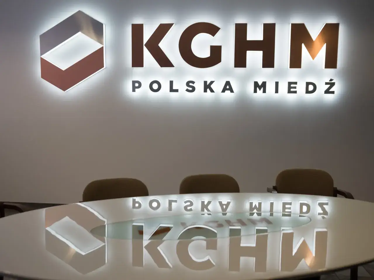 Logo KGHM Polska Miedź i odbicie na stole. Czy Konfederacja poprze ustawę o obniżeniu podatku miedziowego w zamian za ustępstwa?