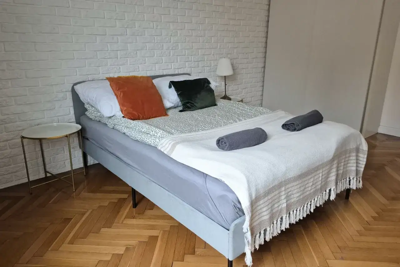Przytulna sypialnia z łóżkiem, poduszkami i kocem. Zastanawiasz się, dlaczego od maja 2026 wszystkie domy na wynajem muszą trafić do centralnego rejestru?