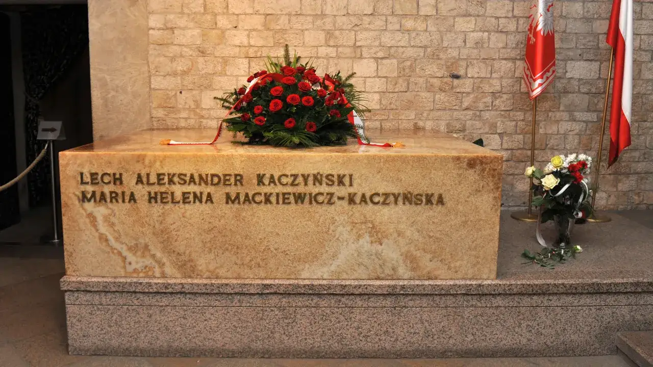 Wieniec z czerwonych róż na grobie Lecha i Marii Kaczyńskich na Wawelu. Obok polskie flagi.