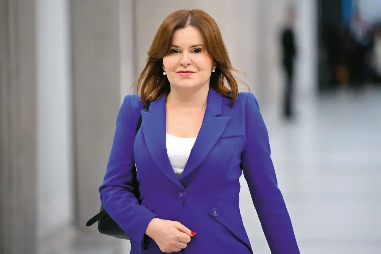 Anna Krupka w niebieskiej marynarce, w tle rozmyte postacie. Czy wiceprezes PiS zarabia?