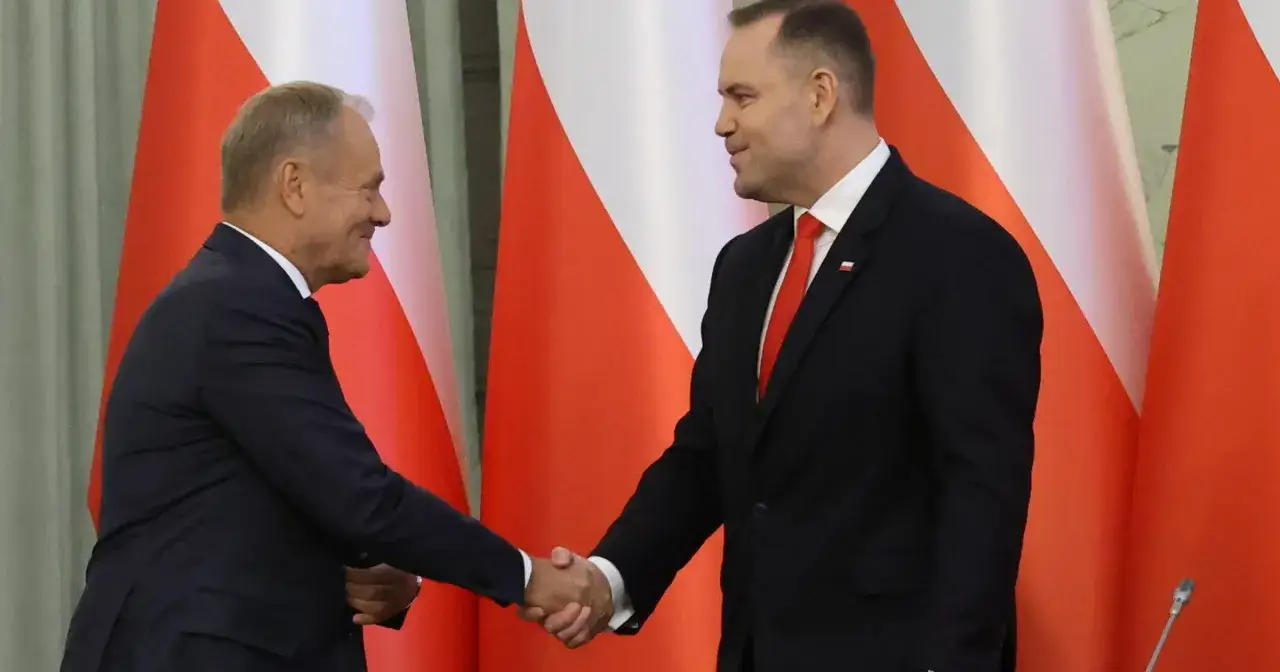 Dwaj politycy ściskają sobie dłonie na tle flag. Czy to początek porozumienia w sprawie ambasadorów, czy tylko pozory?