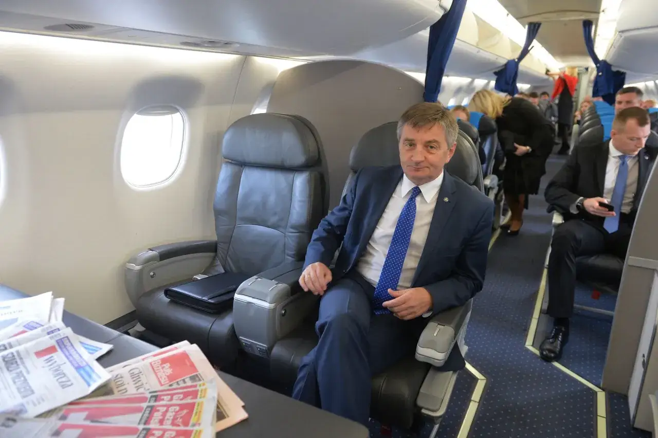 Poseł w garniturze siedzi w samolocie, obok gazety. Czy posłowie PiS będą musieli oddać pieniądze za prywatne loty służbowe?