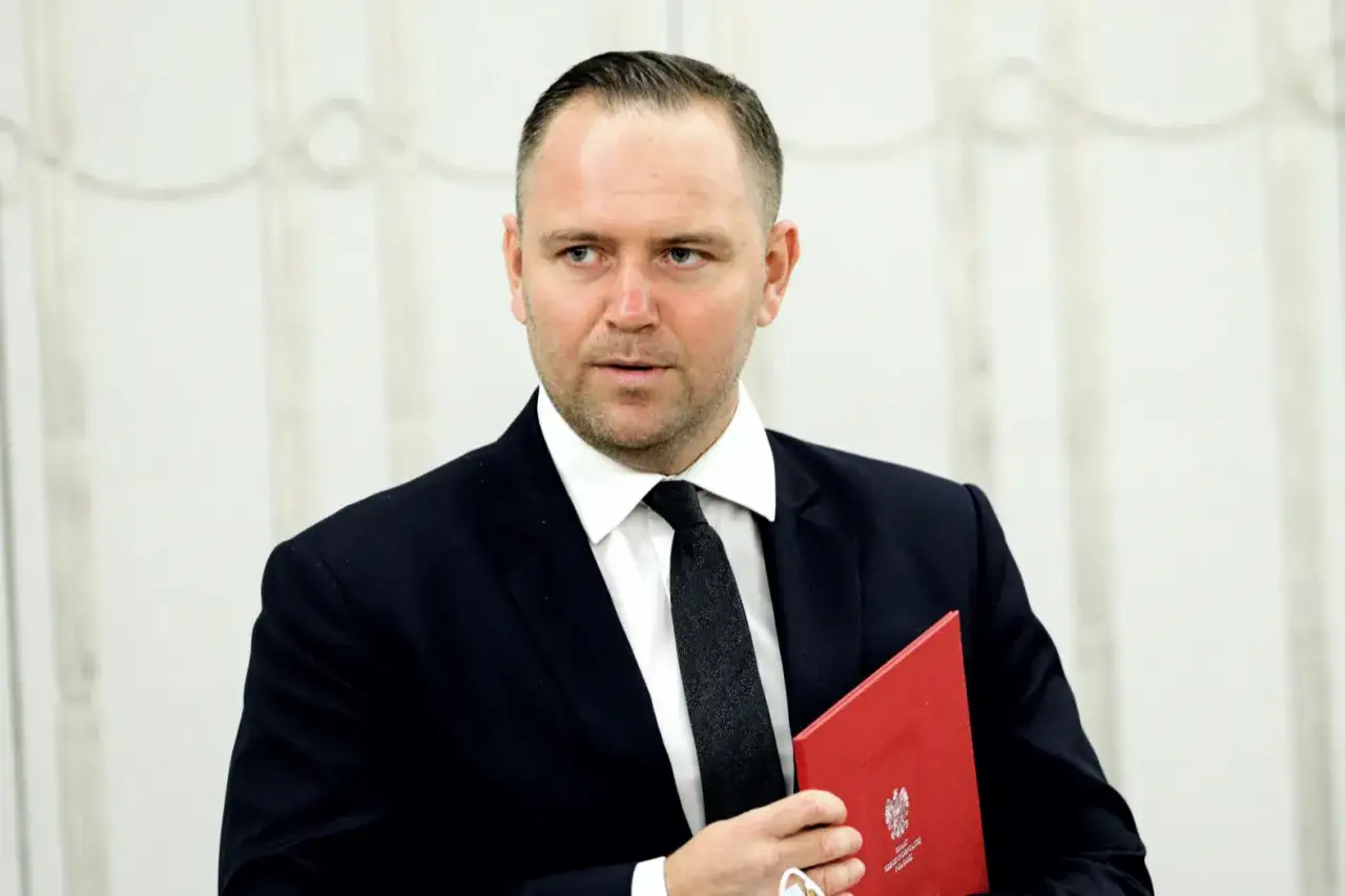 Mężczyzna w garniturze trzyma czerwony folder z orłem. Prawda o kulisach spotkania przedstawicieli Konfederacji z prezydentem Karolem Nawrockim.
