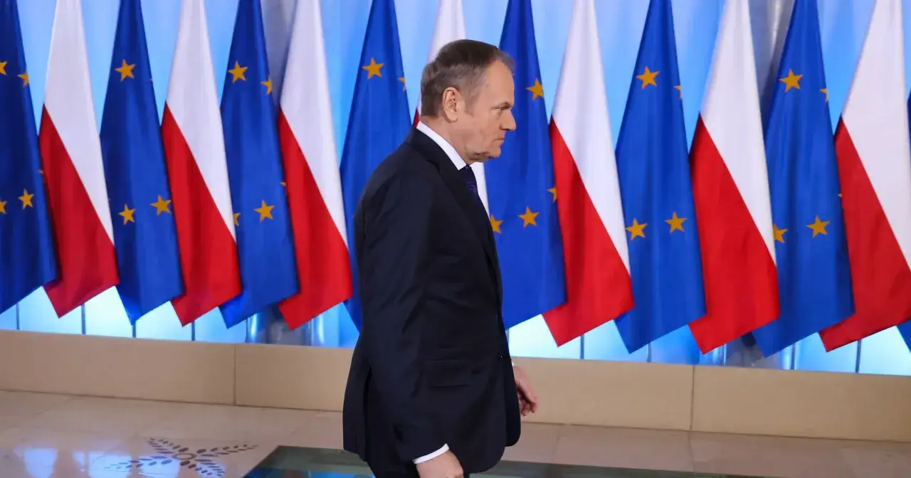 Donald Tusk, w garniturze, na tle flag Polski i UE. Jego rola w Unii Europejskiej jest kluczowa.