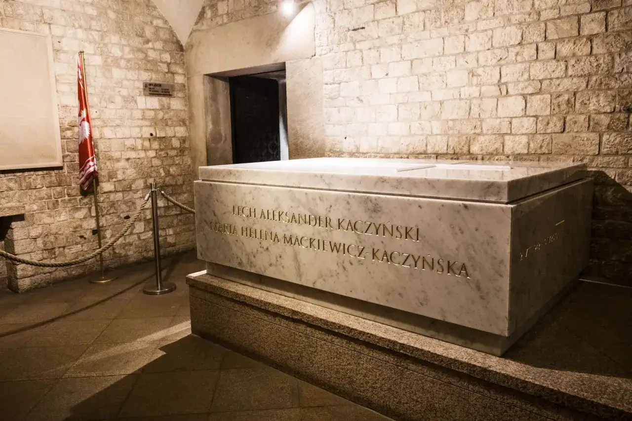 Kamienny grobowiec Lecha i Marii Kaczyńskich na Wawelu. Obok polska flaga.