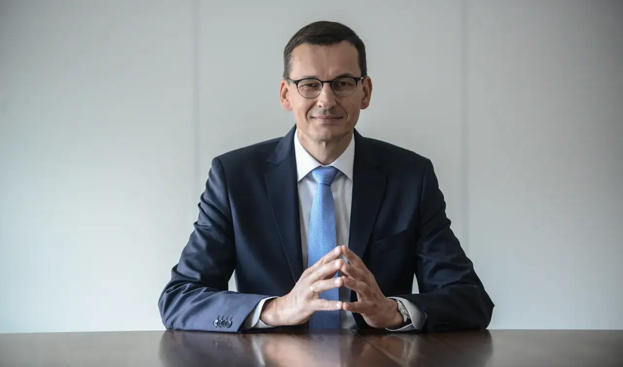 Mężczyzna w garniturze i okularach siedzi przy stole. Zastanawiasz się, ile zarabia Morawiecki?