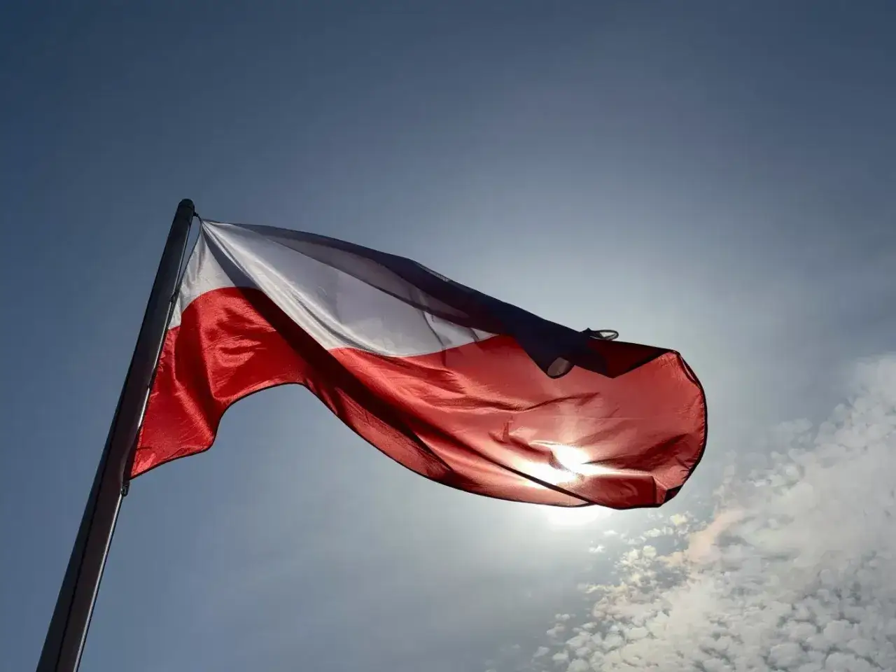 Biało-czerwona flaga Polski faluje na wietrze. W tle niebo, symbolizujące wolność i nadzieję, jak w szczegółach projektu ustawy o 